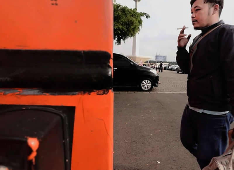 Street photo showing an orange bus aligned with a black car in the background, where matching black areas create a seamless visual illusion.