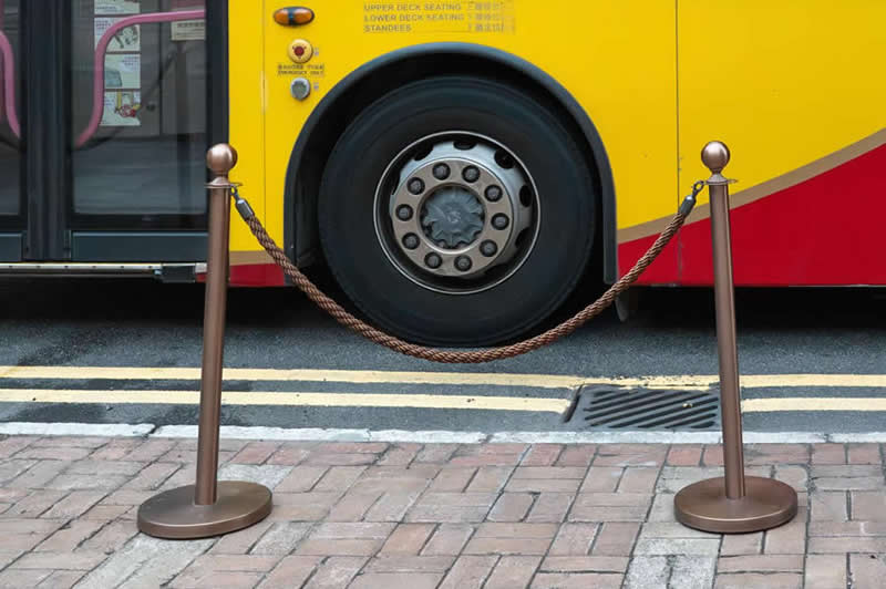 Street photo of a bus wheel centered between two posts connected by a rope, creating a balanced and symmetrical composition.