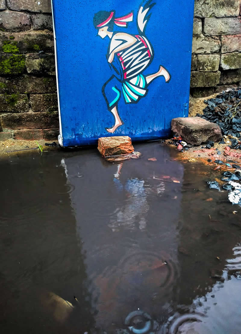 Street photo of a mural of a running figure reflected in a puddle, creating an illusion where the reflection completes the lower part of the figure.