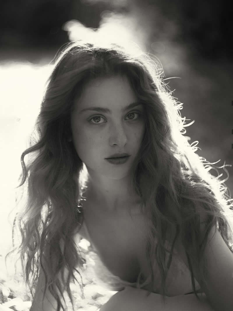 Black and white portrait of a woman with long hair illuminated by strong backlight, creating a glowing halo effect and a soft, ethereal atmosphere.