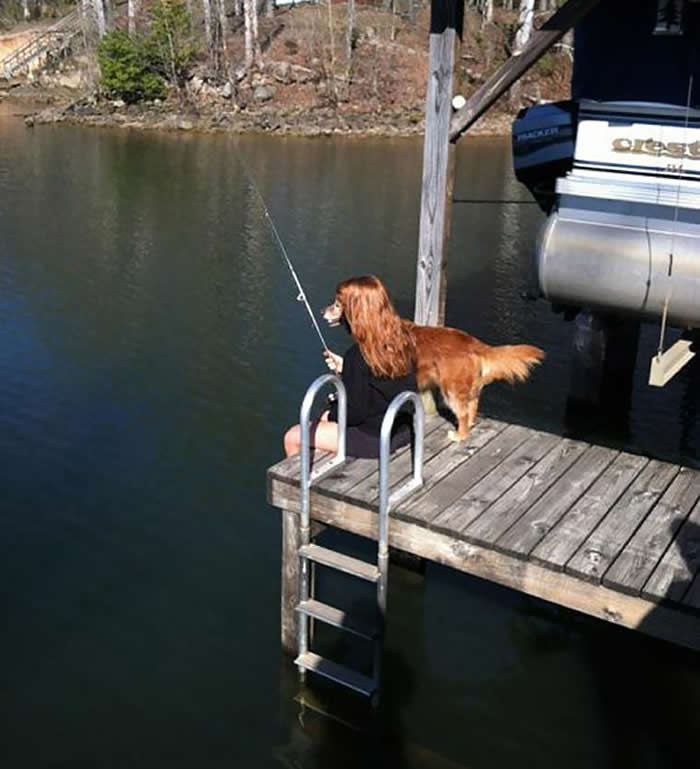 A perfectly timed optical illusion on a wooden dock where a golden retriever&rsquo;s head is positioned exactly over the shoulders of a seated woman, making it look like a dog with a human body is holding a fishing rod.