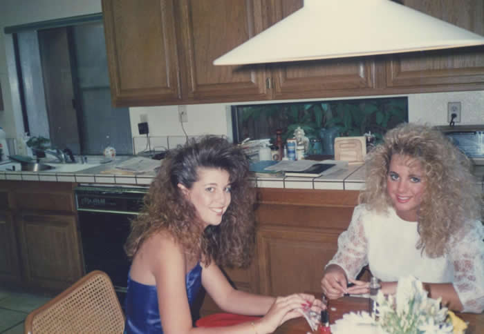 Teenage girls wearing prom dresses in kitchen, 1980s