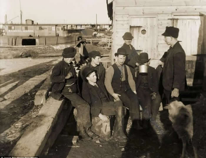 Here are the members of "The Montgomery Guards" street gang, lounging by the docks near the Five Points District in Lower Manhattan, 1900. Photographer: Jacob Riis.
