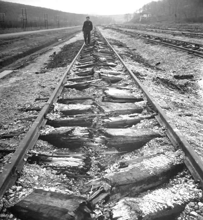Man walking along railroad tracks that have had the ties destroyed by retreating Germans with a &ldquo;Schwellenpflug&rdquo; railroad plough in Belgrade, Yugoslavia. (1945)