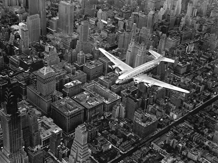 Aerial View of a Douglas DC-4E Passenger Plane Flying Over Midtown Manhattan, New York, 1939.
