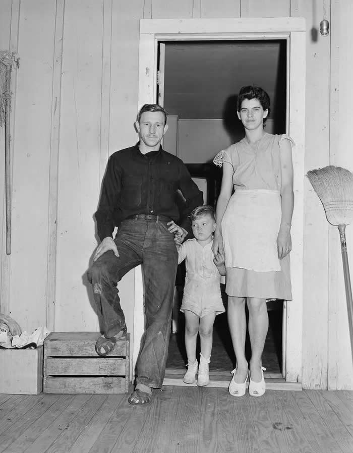Mr. and Mrs. Tommy Swafford and their son in the doorway of their four room house; they pay $9 monthly rental plus $2.50 for electricity.