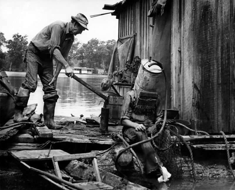 A Mississippi River pearl diver, using a car&rsquo;s old gas tank for a helmet, prepares to descend into the river, 1938.
