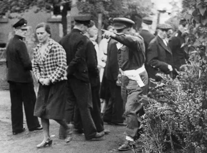 A British soldier scolding a German civilian for laughing at a screening of concentration camp conditions. She was ordered to rewatch the film. (May 1945)