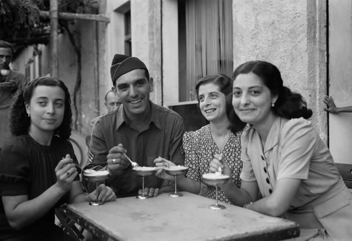 American soldier eats ice cream with his Sicilian cousins at a sidewalk caf&eacute; in Palermo. 1943. Photo: Nick Parrino.