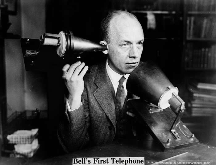 Bell's First Telephone: A man using Alexander Graham Bell's first telephone. Photo published in the Detroit News between 1915 and 1925.