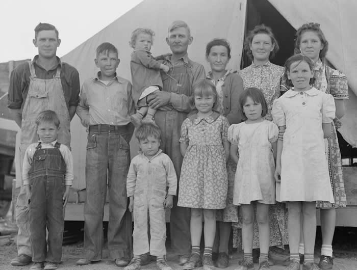 A migrant farm worker poses with his wife and their ten children at a labor camp in California in 1939. The family had traveled from Mangrum, Oklahoma, leaving behind the hardships of the Dust Bowl era in hopes of finding seasonal work.