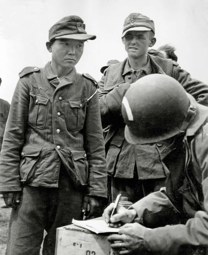 A soldier registers prisoners of war on June 7, 1944, at Utah Beach (France). Among them is Yang Jong-Kyoung, a Korean born in 1920. He enlisted in the Japanese Kwantung Army in 1938, was captured by the Soviet army at Nomohan and then recaptured by the Germans at the Battle of Kharkov in 1943.