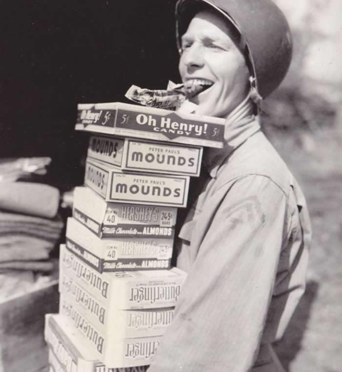 A happy soldier carrying candy rations for his fellow troops in 1944.
