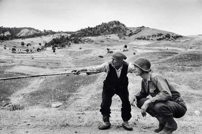 Sicilian peasant telling an American officer which way the Germans had gone, 1943