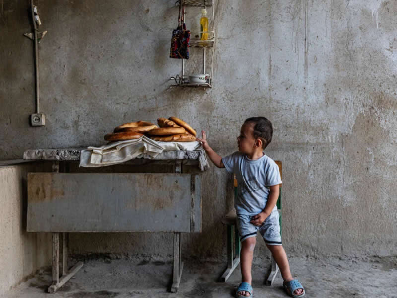 Little Asilbek touching the hot bread, straight out of the family tandoor in Samarkand (Uzbekistan). Food for the Family supported by The Felix Project. | Michela Balboni and Federico Borella/World Food Photography Awards sponsored by Bimi