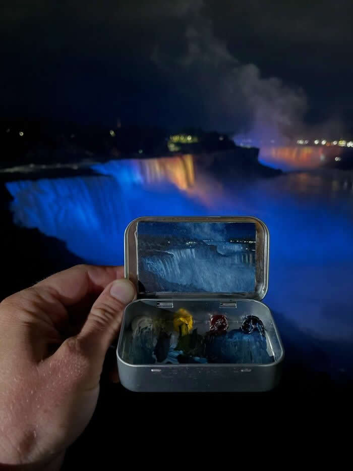 These 40 Tiny Altoid Tin Paintings by Remington Robinson Are Pure Pocket-Sized Magic 58 A hand holds an open Altoid tin at night in front of the glowing blue waters of Niagara Falls, revealing a miniature painting by Remington Robinson of the illuminated falls, with a tiny dark-toned paint palette arranged in the bottom half.