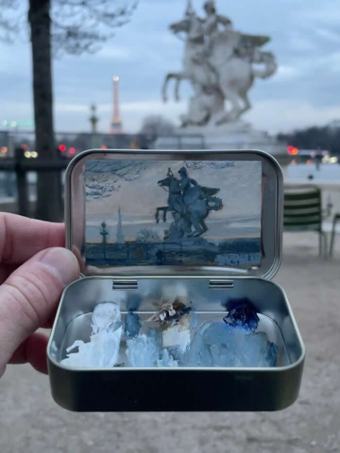 These 40 Tiny Altoid Tin Paintings by Remington Robinson Are Pure Pocket-Sized Magic 78 A hand holds an open Altoid tin in a Paris square at dusk, revealing a miniature painting by Remington Robinson of an equestrian statue silhouetted against the skyline, with a tiny paint palette of whites, grays, browns, and deep blue in the bottom half.