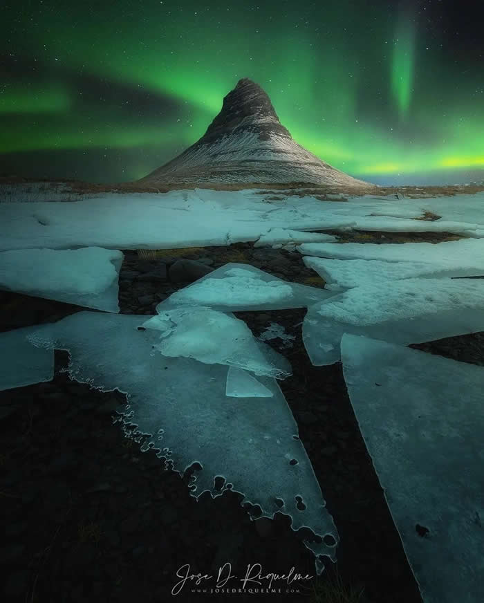 Beauty of the Earth: 33 Epic Landscape Views That Prove Nature Is the Greatest Artist 46 A snow-covered mountain rises beneath green aurora lights, with broken ice sheets filling the foreground and a starry night sky stretching across the scene.