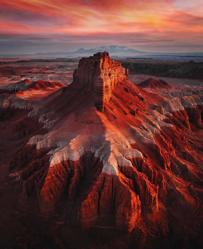 Beauty of the Earth: 33 Epic Landscape Views That Prove Nature Is the Greatest Artist 68 A towering red desert butte glows in warm sunset light, surrounded by deeply eroded canyons and layered rock formations beneath a dramatic pink and orange sky.