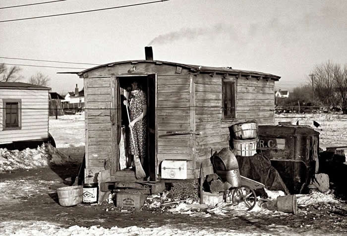 Mrs. Charles Binning sweeping the steps of her shack in Shantytown, Spencer, Iowa during the Depression. 1936.