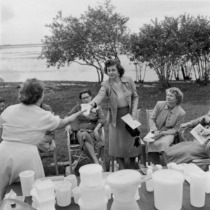 Passing round the product at an outdoor Tupperware party. Hosts had a strict dress code &ndash; skirts and stockings were mandatory. 1955