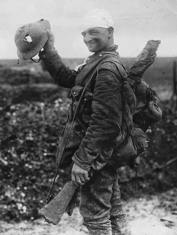 Happy (and very lucky) British soldier shows off his damaged helmet, 1917 (Western Front, The First World War)