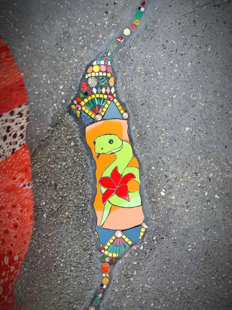 A snake dancing on your sidewalk, adorned with a majestic red