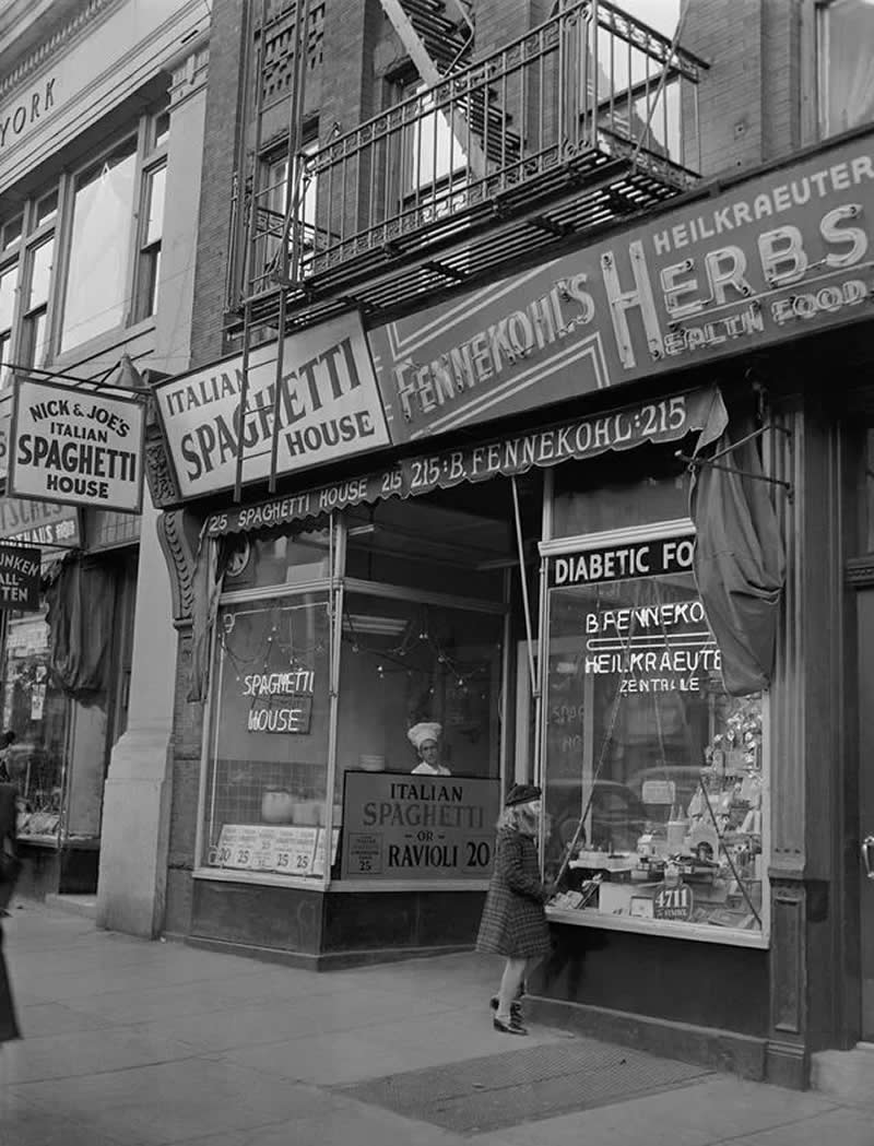 1942. 86th Street. An Italian Spaghetti Store next to a German Health Food Store share a building front