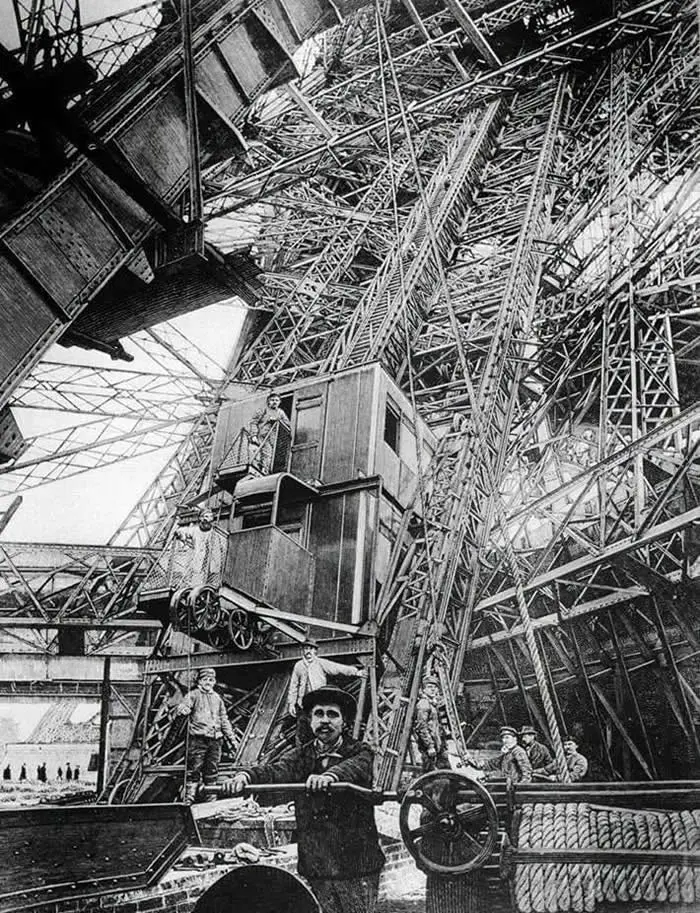 The elevator is shown at the first level of the Eiffel Tower, during its construction.
