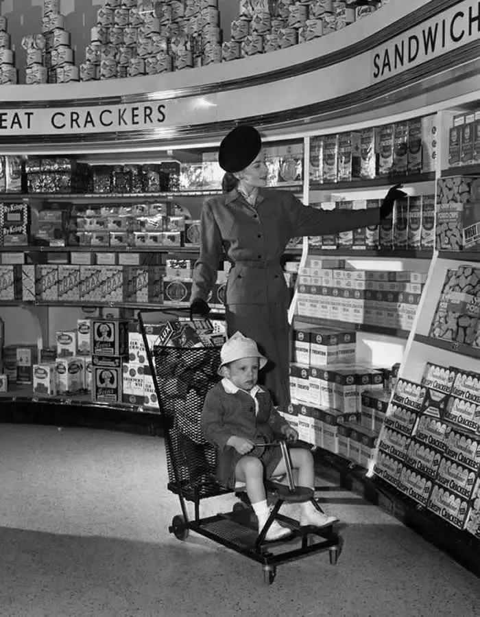 This impeccably dressed woman shopping for groceries with her son. 1945