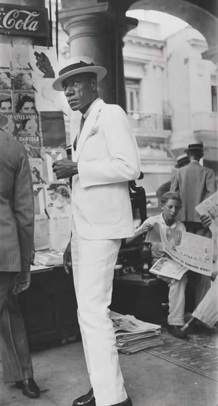 A Cuban man in a white suit walks through downtown Havana, 1933. (Photo by Walker Evans).