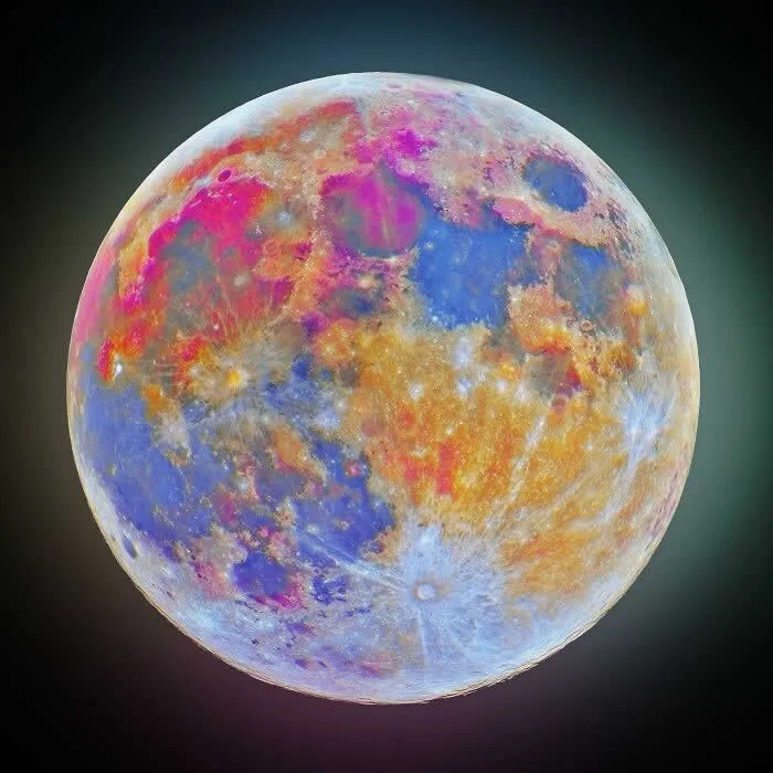 Full Moon displaying vivid blue, pink, purple, and golden surface patterns revealed through ultraviolet and infrared filters against a dark background.