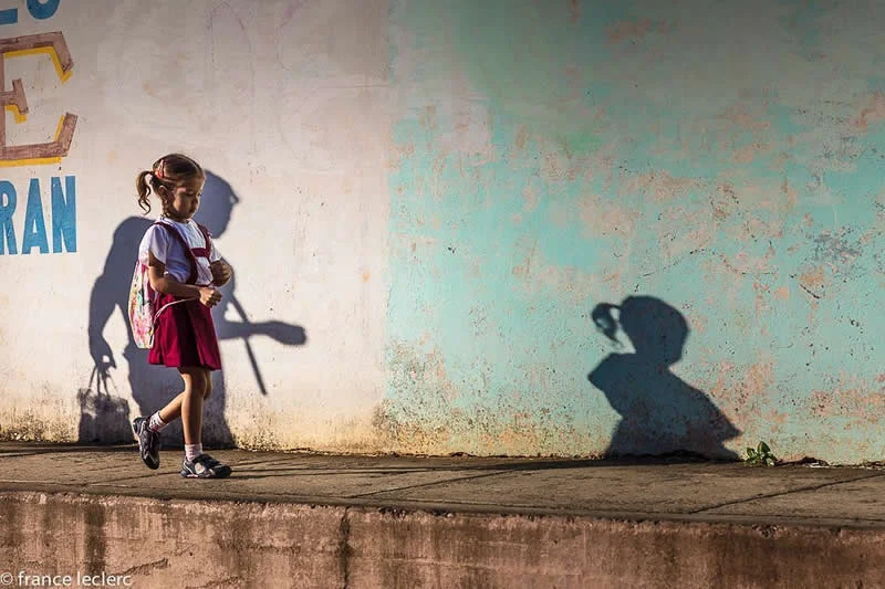 Capturing Humanity: Award-Winning Photographer France Leclerc Explores Life Around the World 65 A father (the shadow) walks her daughter to school in Baracoa, Cuba - Street and Documentary Photography by France Leclerc