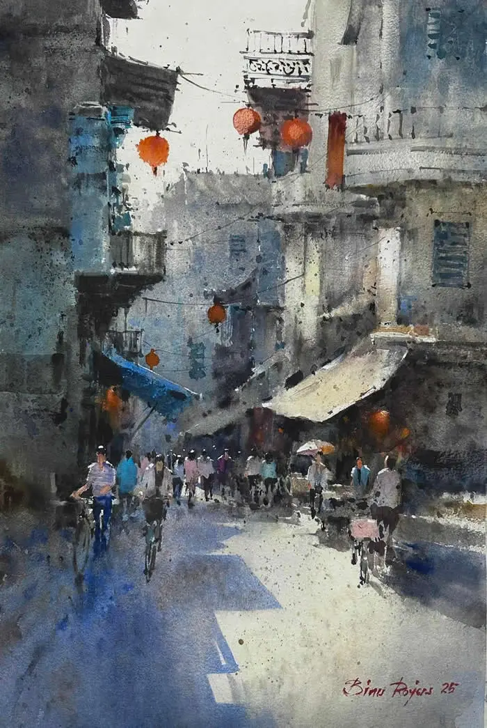 Watercolor painting by Indian artist Binu Rojers titled Street, depicting a busy narrow street lined with old buildings, orange hanging lanterns, awnings, and pedestrians walking through contrasting areas of sunlight and shadow.