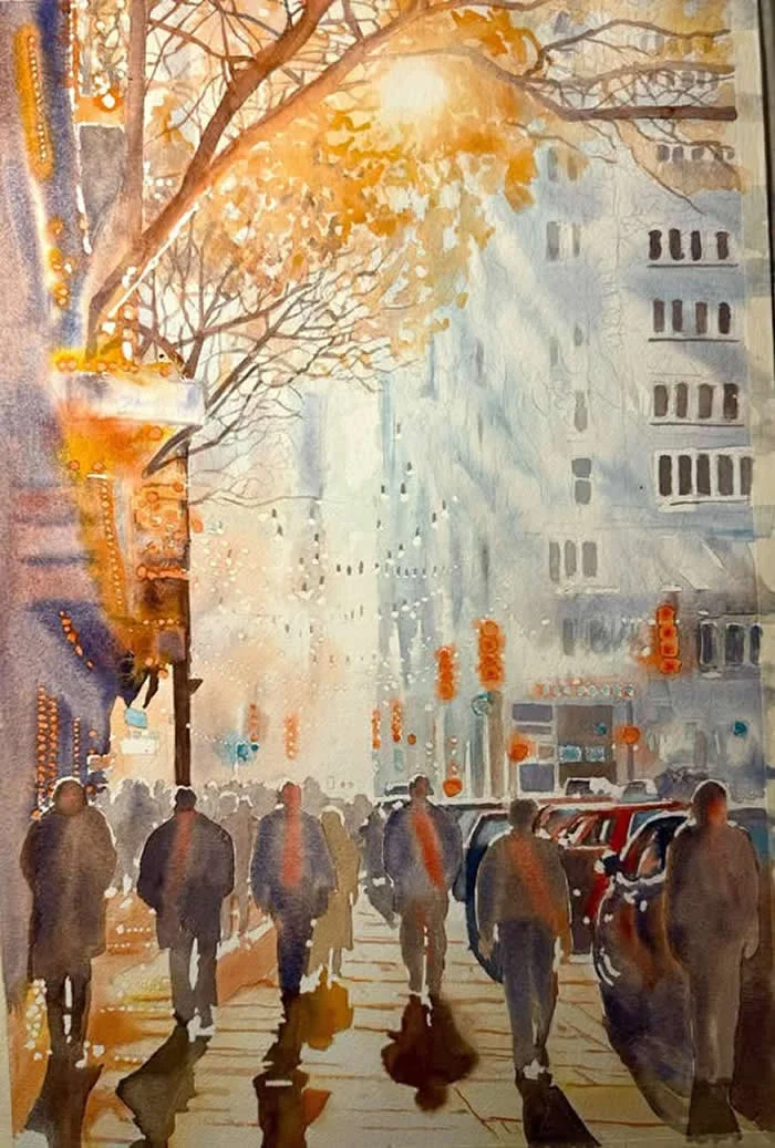 Watercolor painting titled Bloom by Italian artist Mario Tartari, depicting pedestrians walking along a sunlit city street beneath golden autumn leaves, with tall buildings, parked cars, and long shadows stretching across the pavement.